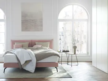 Rosa Design Polsterbett in einem hellen Schlafzimmer.