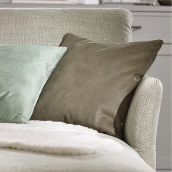 Hellgrüner Longchair eines Ecksofas, das mit Kissen und Decke dekoriert ist.