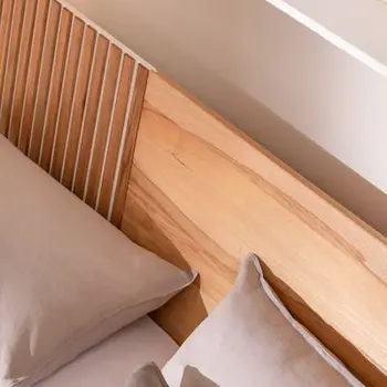Ansicht von oben auf ein Bett, das ein Kopfteil aus hellem Holz hat mit Lamellenakzenten auf der linken Seite.