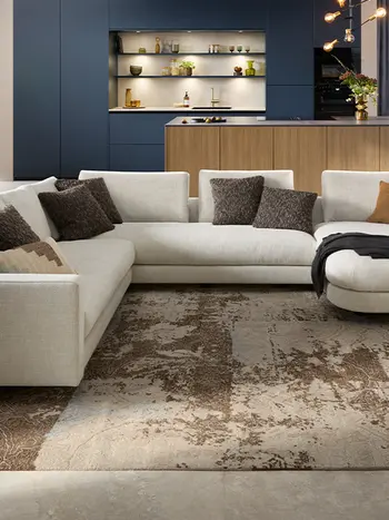 Große beige Designwohnlandschaft vor einer Designküche mit Kücheninsel und blauen Hochschränken.