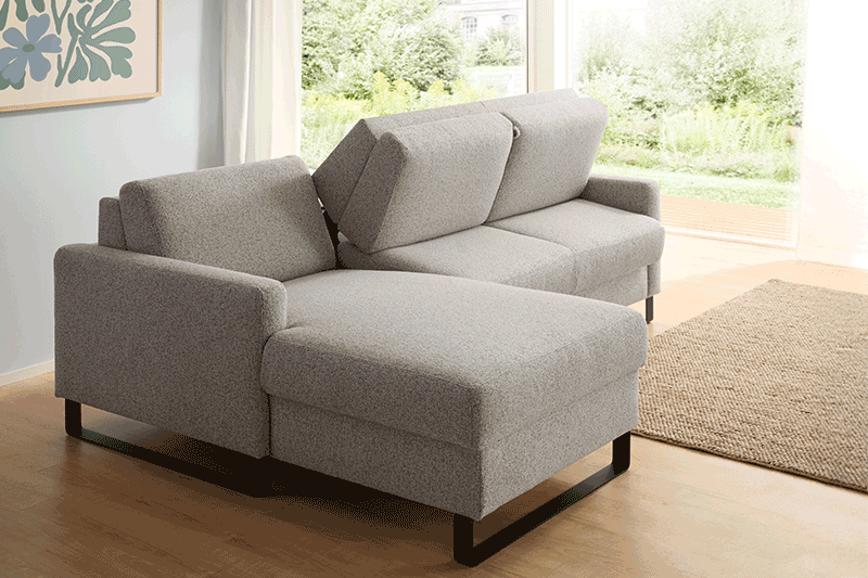 Hellgraues Schlafsofa mit integrierter Matratze zum Ausklappen in hellem Wohnzimmer.