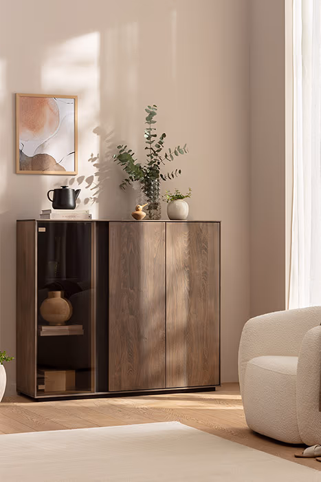 Wohnzimmer mit Sideboard aus dunklem Holz und beigem Sessel.