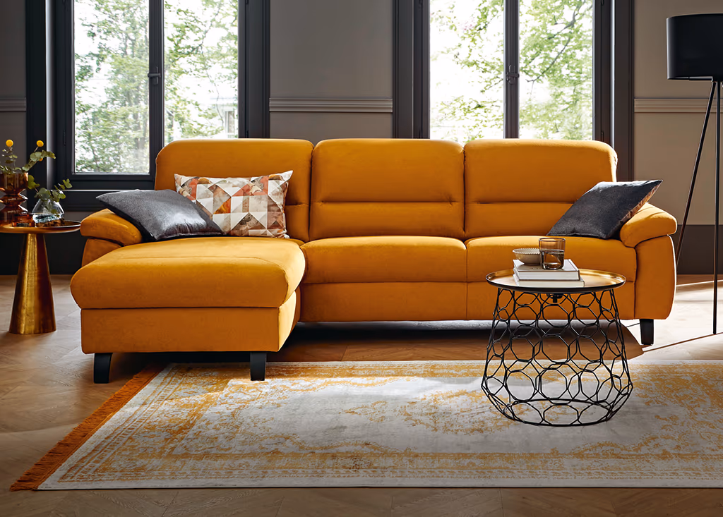 Orangefarbene Stoffcouch mit Kissen und passendem Couchtisch in gemütlichen Wohnzimmer