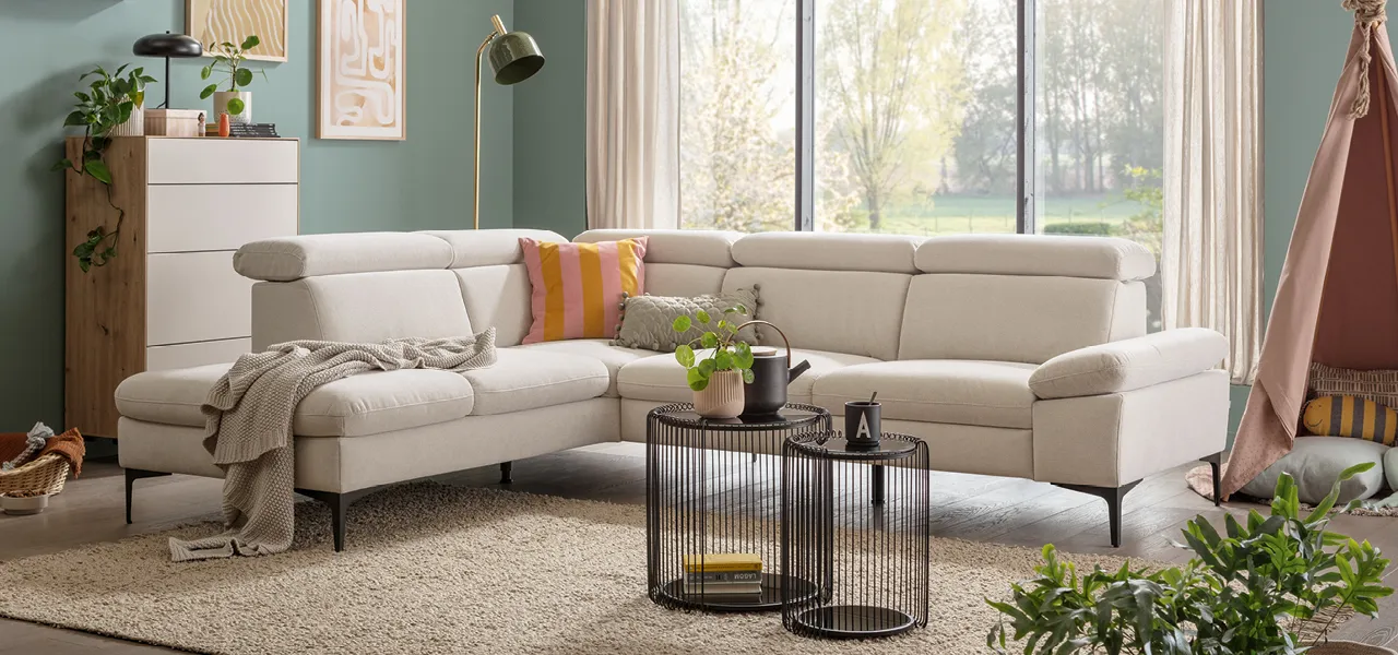 Cremeweisses Ecksofa mit orangefarbenem Kissen in Wohnzimmer