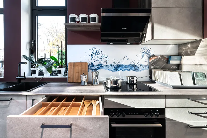 Contur Kuechenzeilein weiss mit offener Schublade und stylischer Dunstabzugshaube.