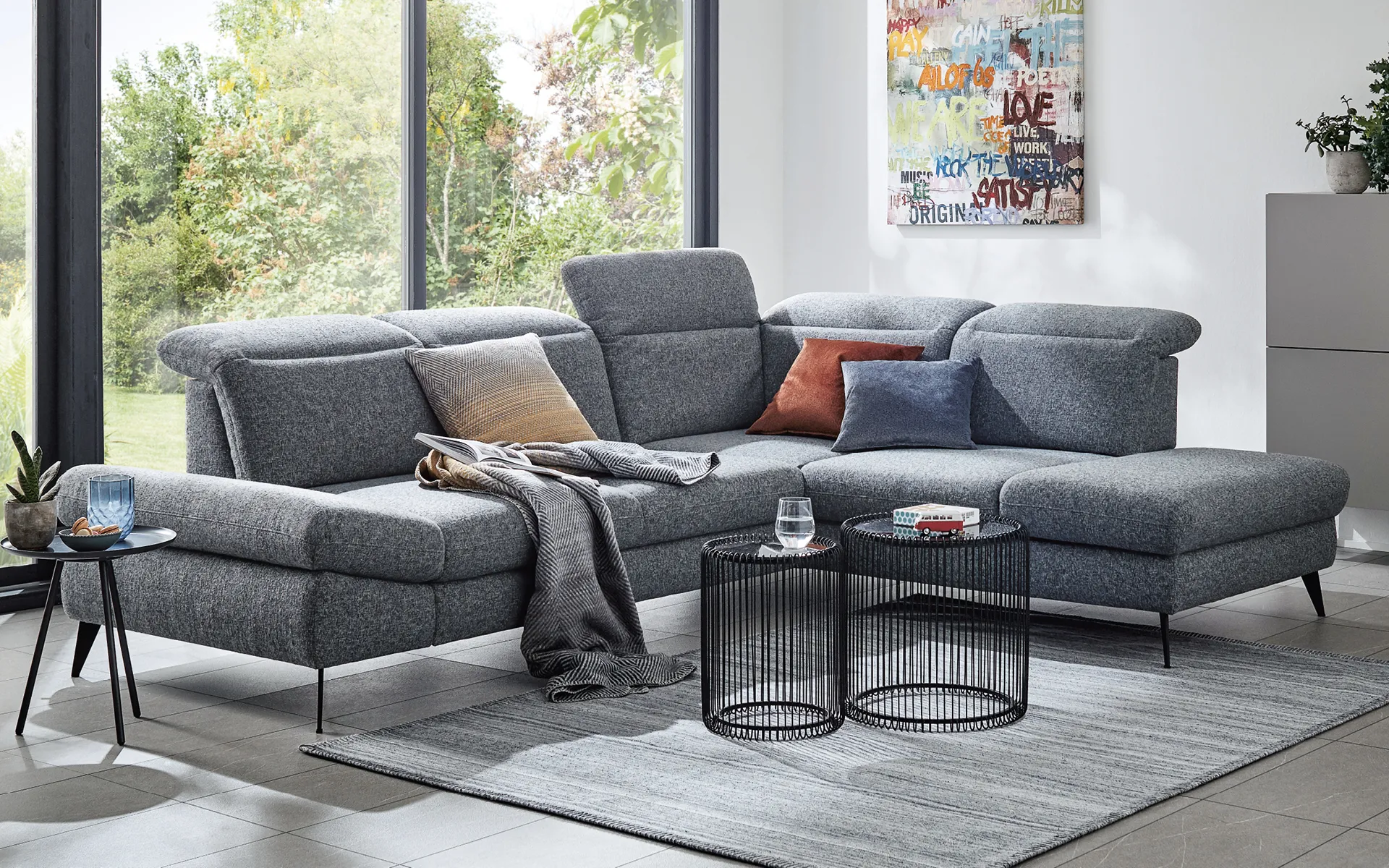 Blaugraues Sofa vor Panoramafenster in modernem Wohnzimmer
