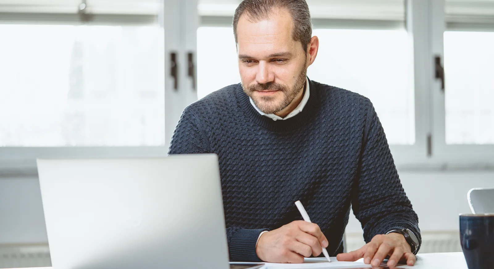 Mann am Telefon vor Laptop sitzend