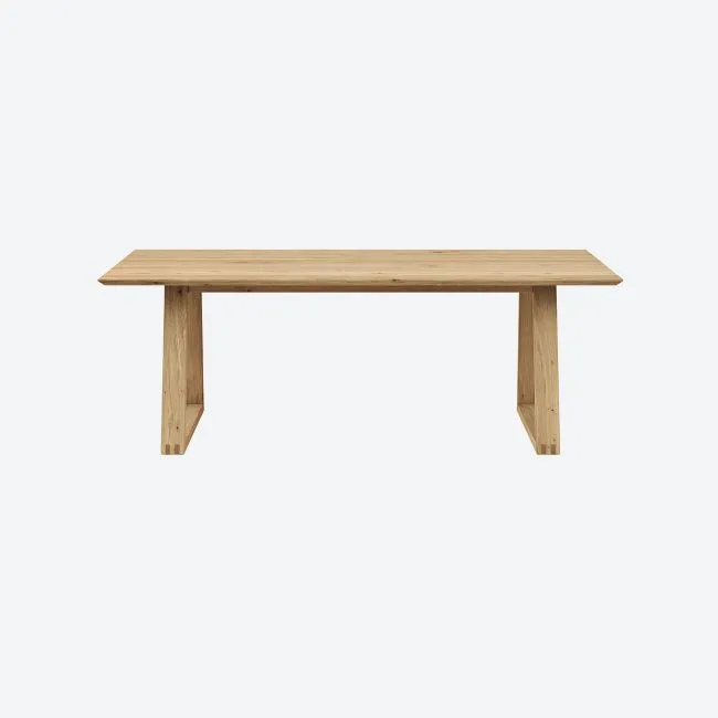 Esstisch aus hellem Massivholz vor weißem Hintergrund.