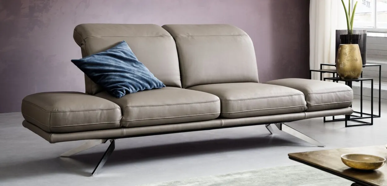 Ledersofa: drehbare Sitzflächen, blaues Kissen und auberginefarbene Wand, Hände mit Nadel nähen Leder