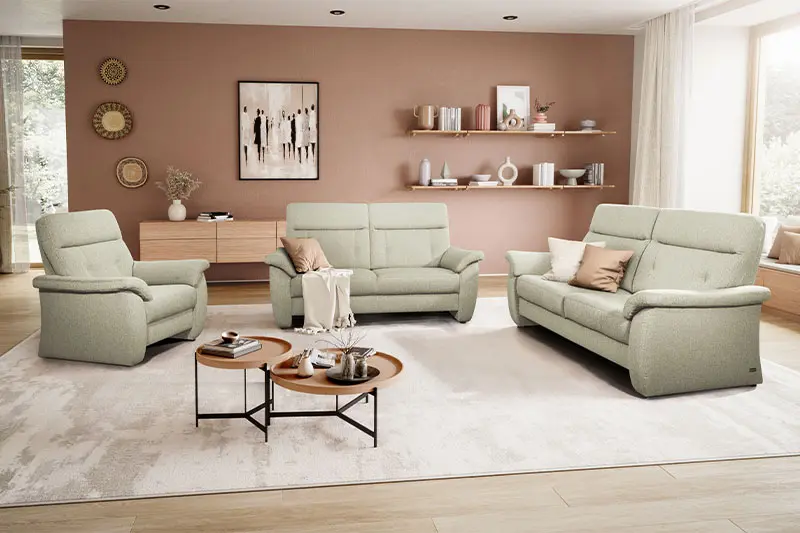 Beiger Sessel, neben zwei beigen Couch Garnituren in einem hellen gemütlichen Raum.