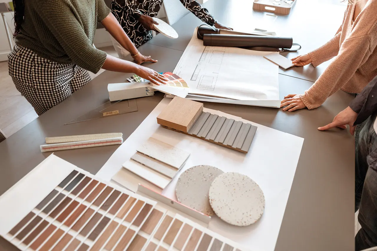 Beratungstisch mit Grundriss, Farbmustern, Holzproben und Materialmustern, professionelle Raumplanung und Innenarchitektur für individuelle Wohnkonzepte.