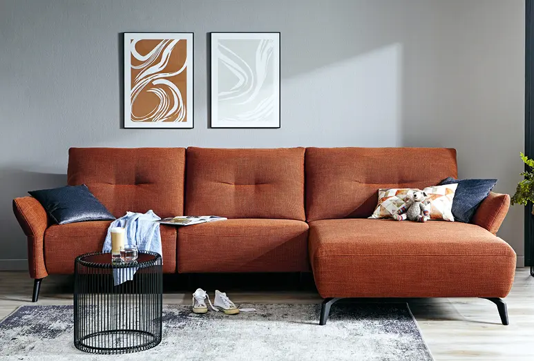 Komfortables Sofa in rostbrauch mit Couchtisch vor grauer Wand, hohe Sitzhöhe für Senioren