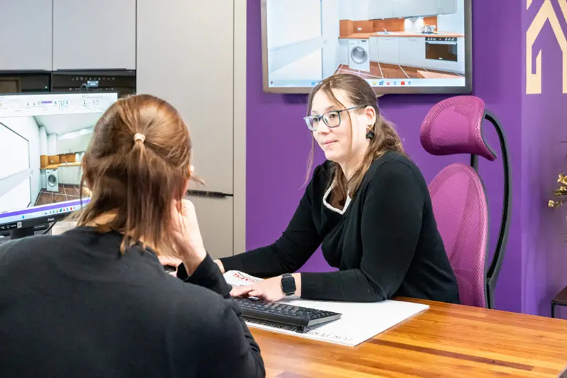 Mitarbeiterin vom Kuechenhaus Gruber im Beratungsgespraech mit Kundin vor Kuechenplan am Computer