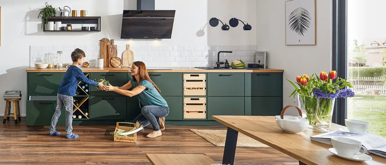 Schicke Küchenzeile im Landhausstil mit grünen Küchenfronten und Holzakzenten