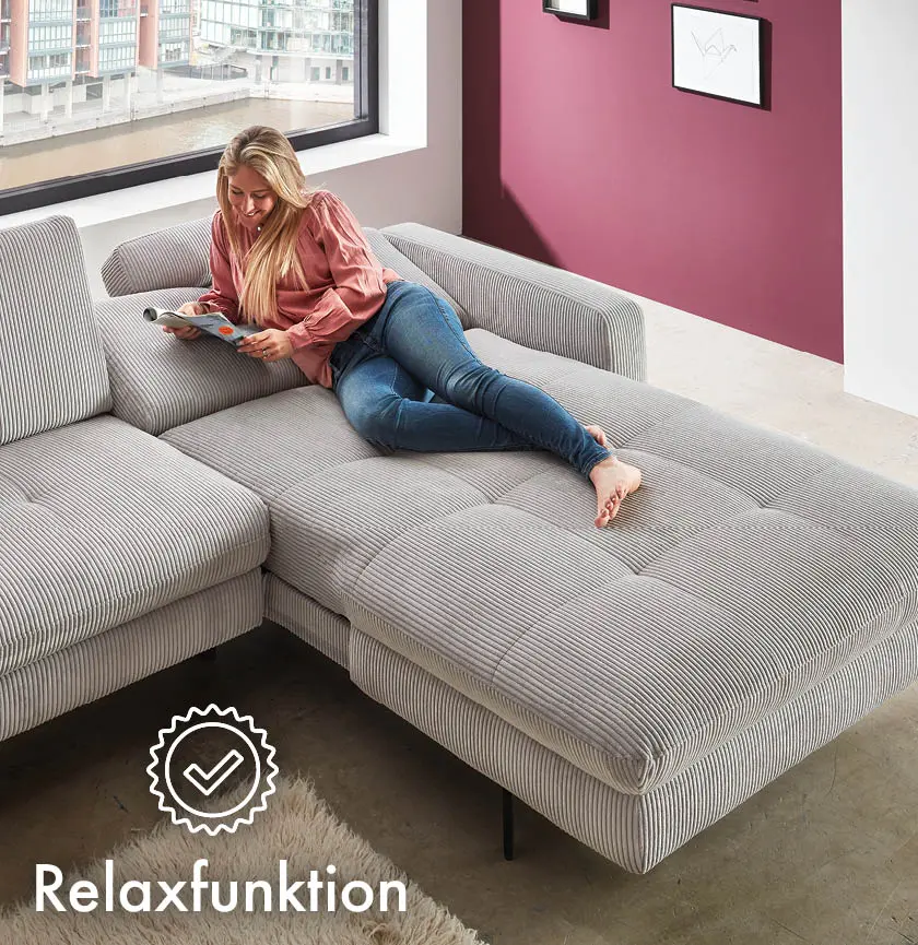 beiges Cordsofa mit Relaxfunktion und Frau darauf liegend