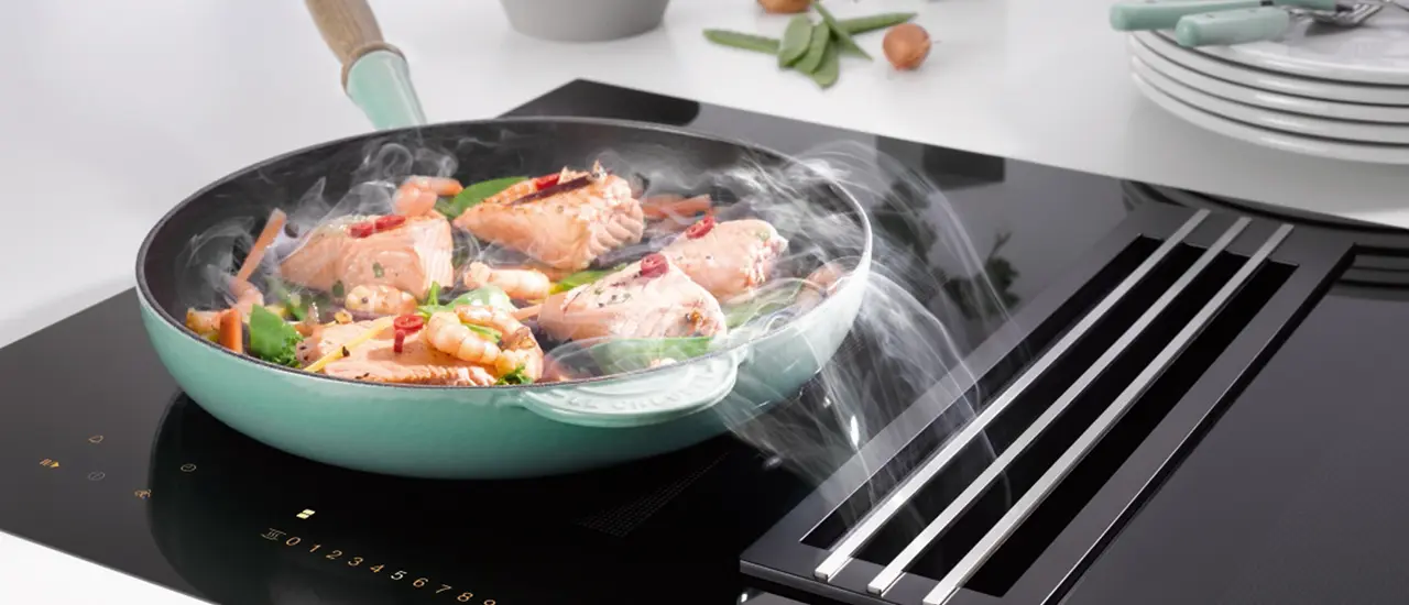 Pfanne mit Garnelen auf Herd mit Muldenlüfter