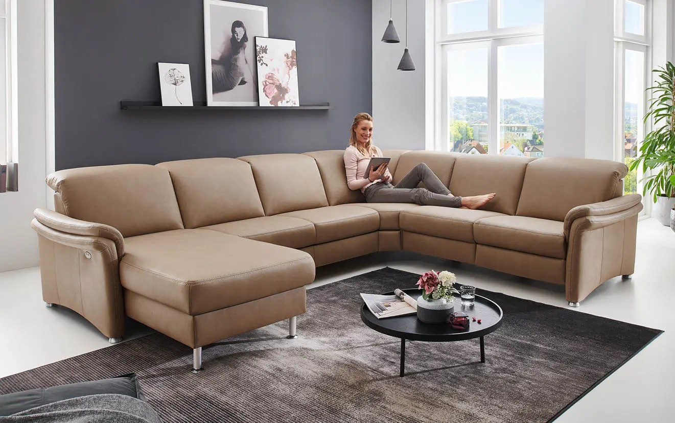 Frau liest auf beigem Leder-Ecksofa