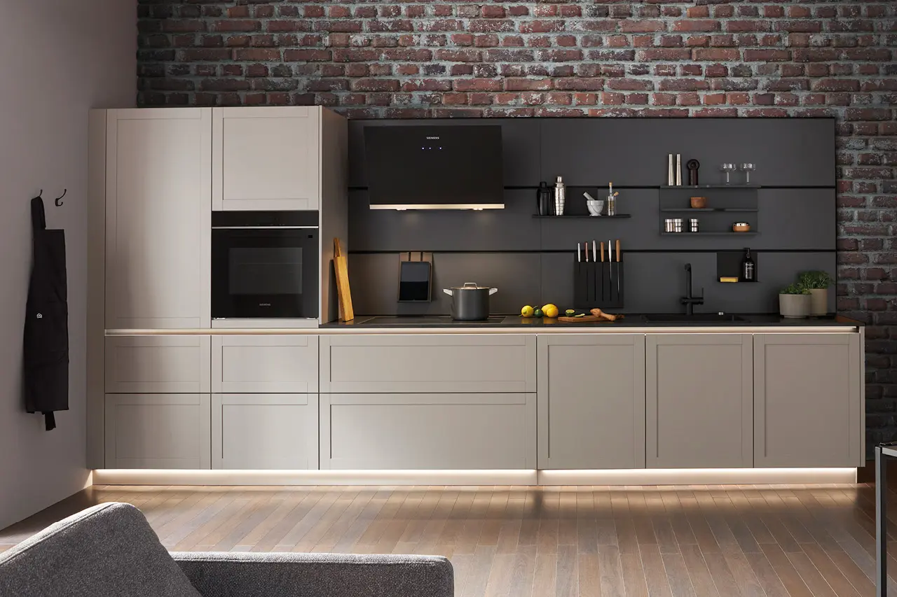 Moderne Einbauküche mit hellgrauen Fronten, dunkler Rückwand, integrierten Elektrogeräten und offener Regalwand vor roter Backsteinwand, geradlinige Küchenplanung im Industrial Stil mit indirekter Beleuchtung