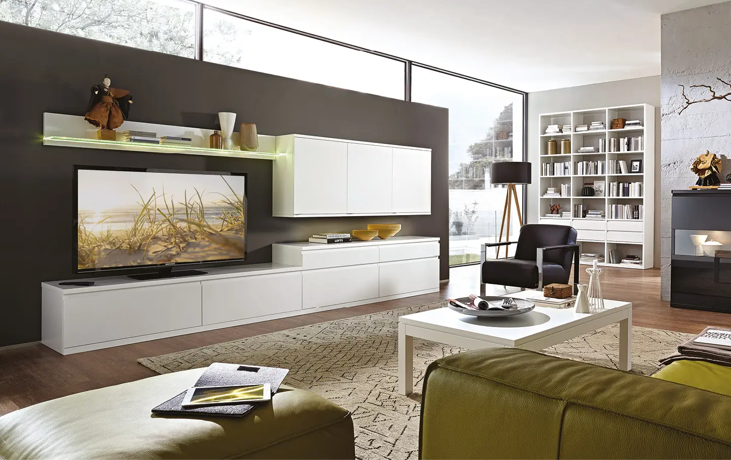 Wohnzimmer mit weißer Wohnwand, Fernseher und großem Fenster