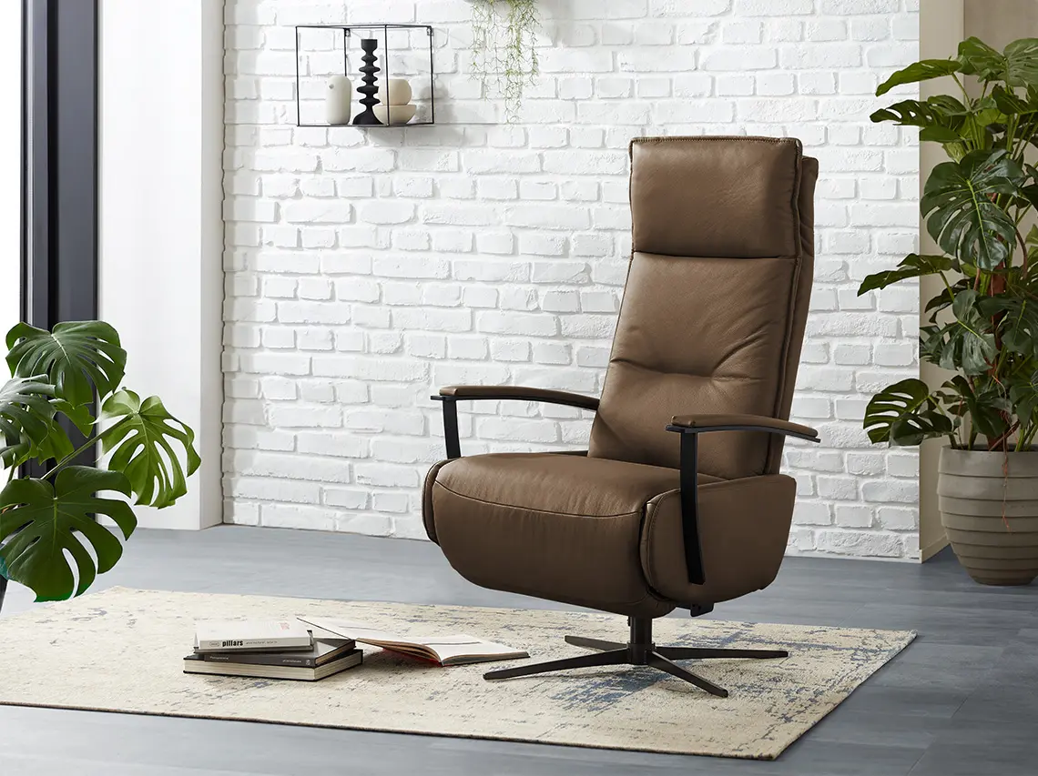 Brauner Ledersessel mit Relaxfunktion vor einer weißen Ziegelwand.