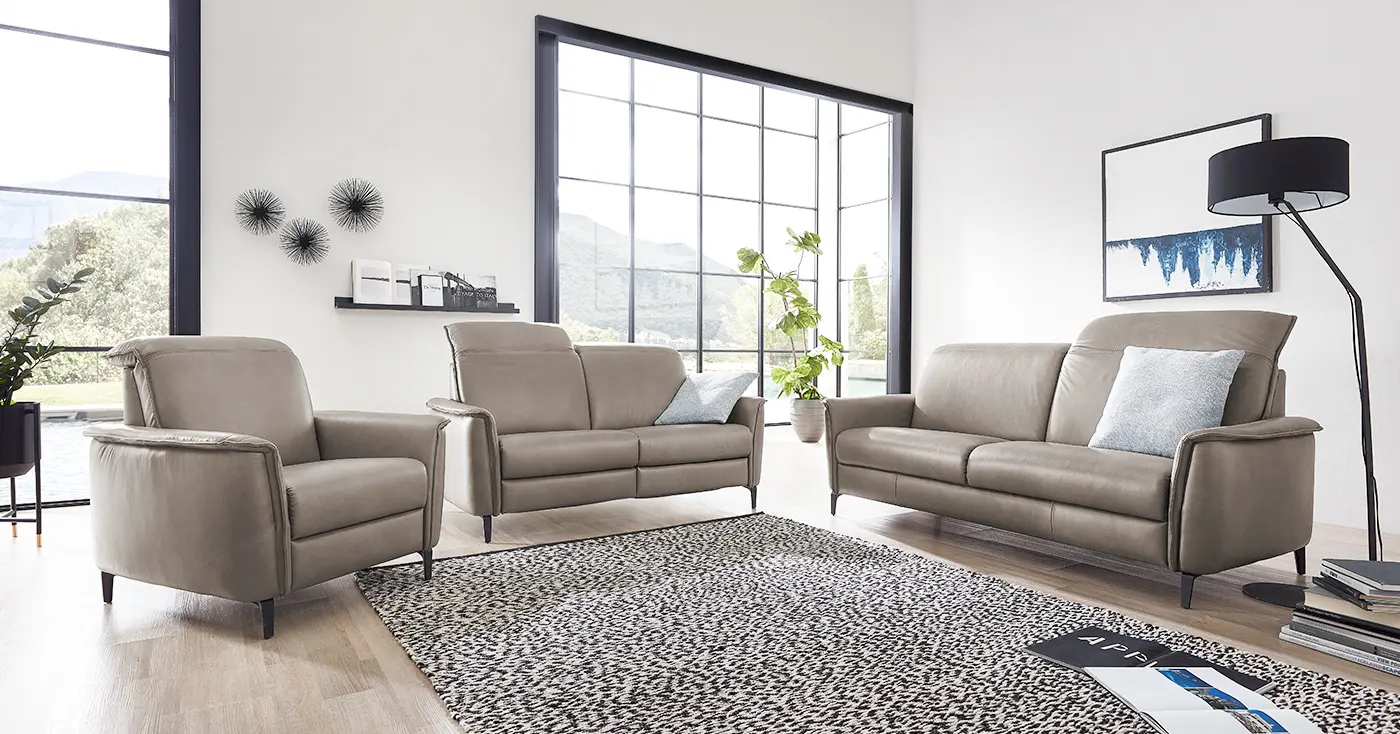 Zwei graubraune Ledersofa Garnituren mit verstellbarer Kopfstütze und einem dazu passenden Sessel.