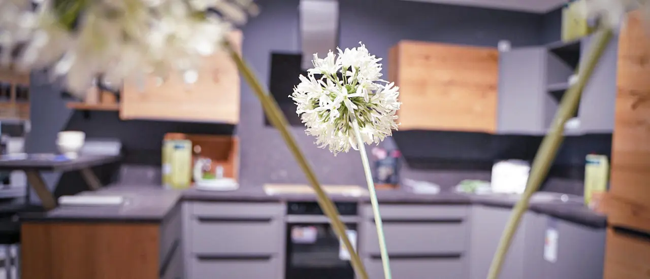 Blumen mit grauer Winkelküche im Hintergrund