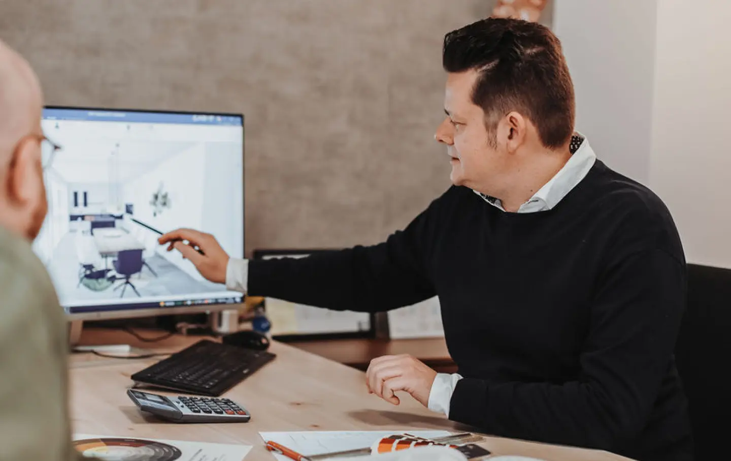 Beratungsgespraech eines Kunden an Tisch mit 3D-Computermodell.