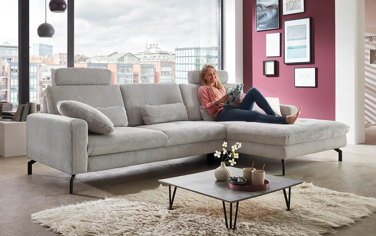 Frau auf grauer Couch liest Zeitungen