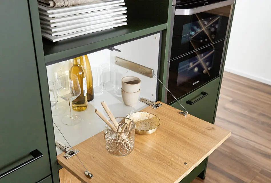 Ausklappbare Arbeitsfläche am Hochschrank als Platzgewinn in kleiner Küche.