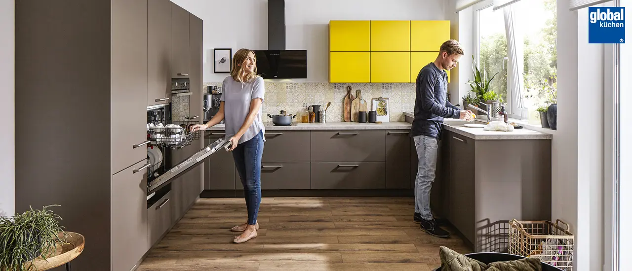 Global Küchen - Paar in grau-brauner U-Küche mit gelben Akzenten
