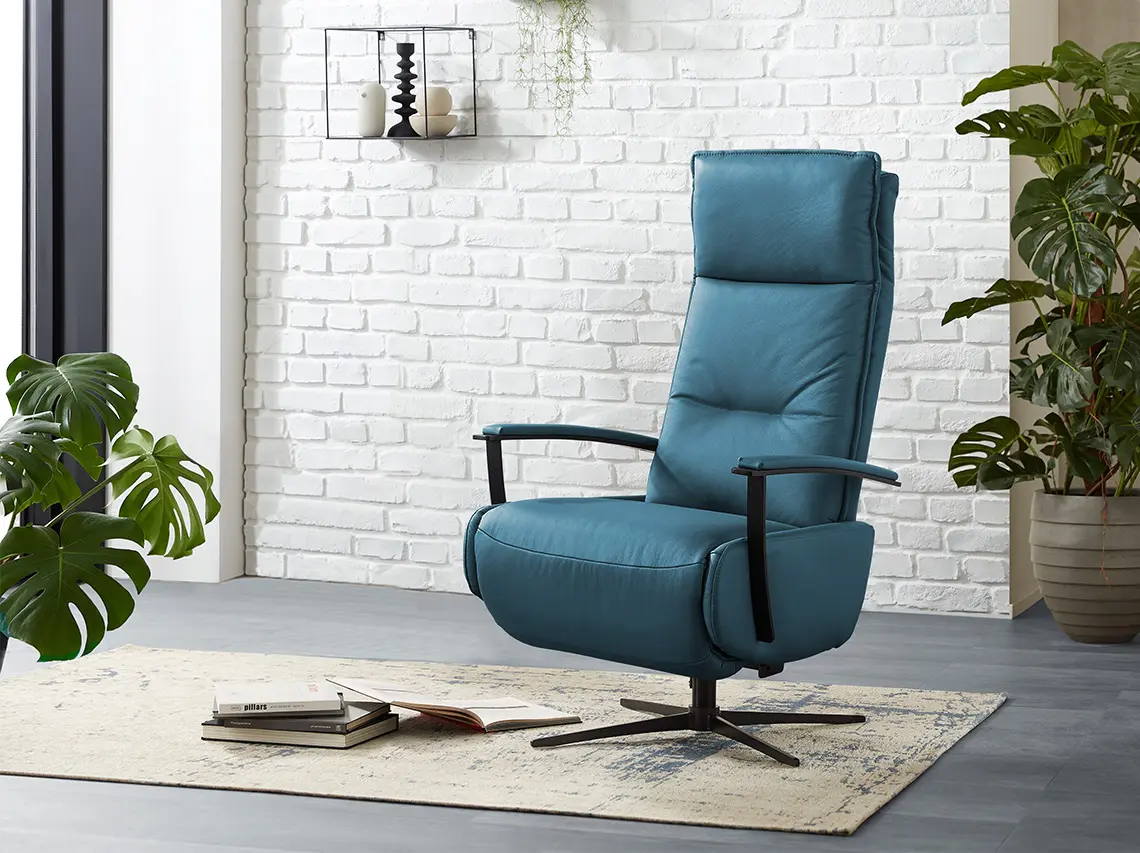 Petrol farbener Ledersessel mit Relaxfunktion vor einer weißen Ziegelwand.