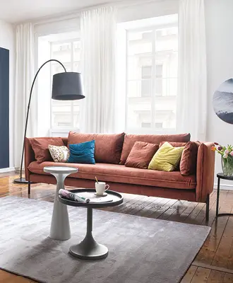 Wohnzimmer mit stylischer Couch in knackigem rot und bunten Kissen.