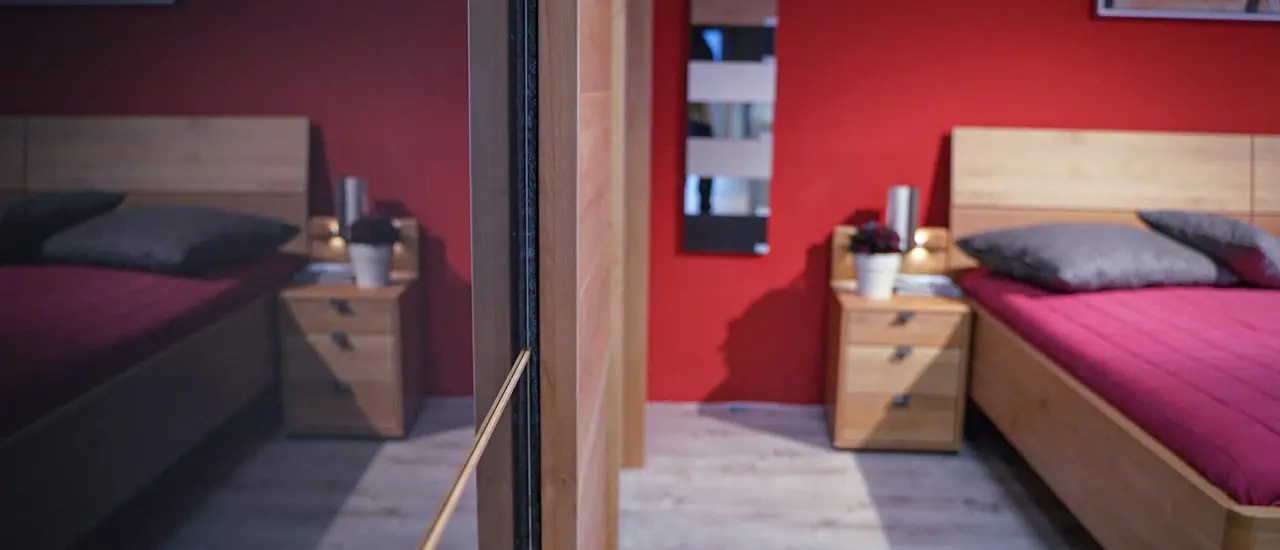 Kleiderschrank aus Holz mit passendem Bett in rotem Schlafzimmer