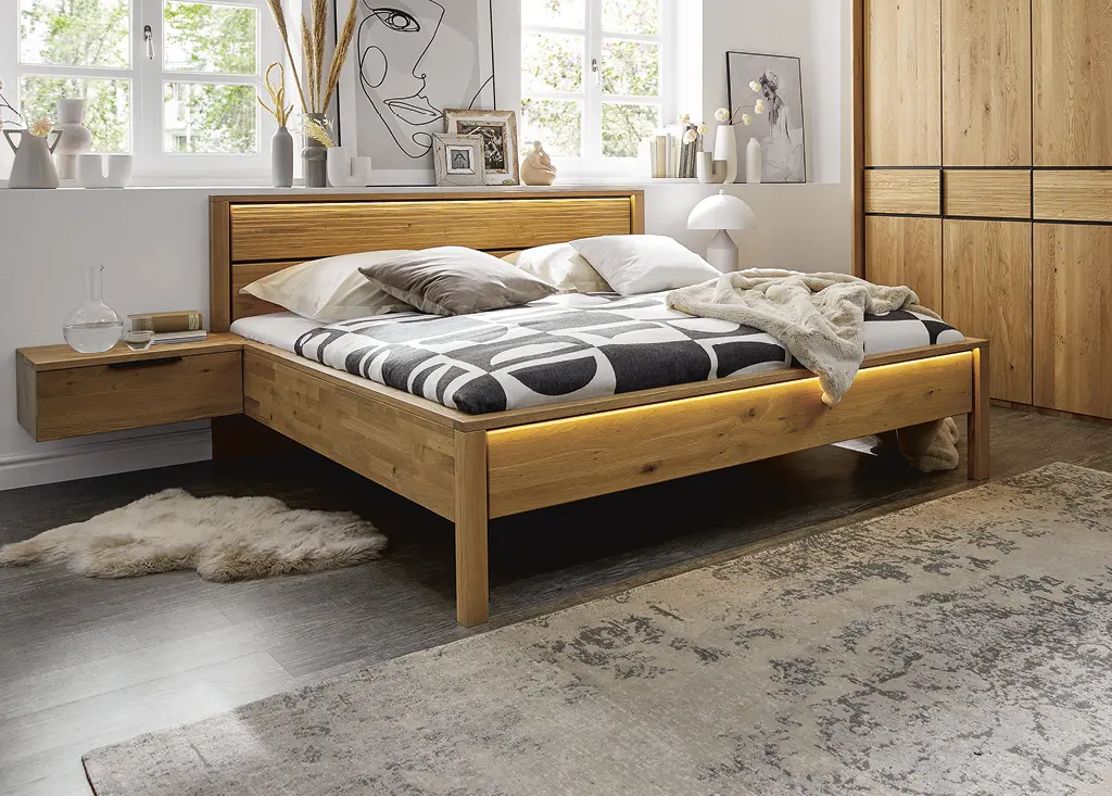 Breites hölzernes Bett und Kleiderschrank mit LED-Beleuchtung in offenem Schlafzimmer