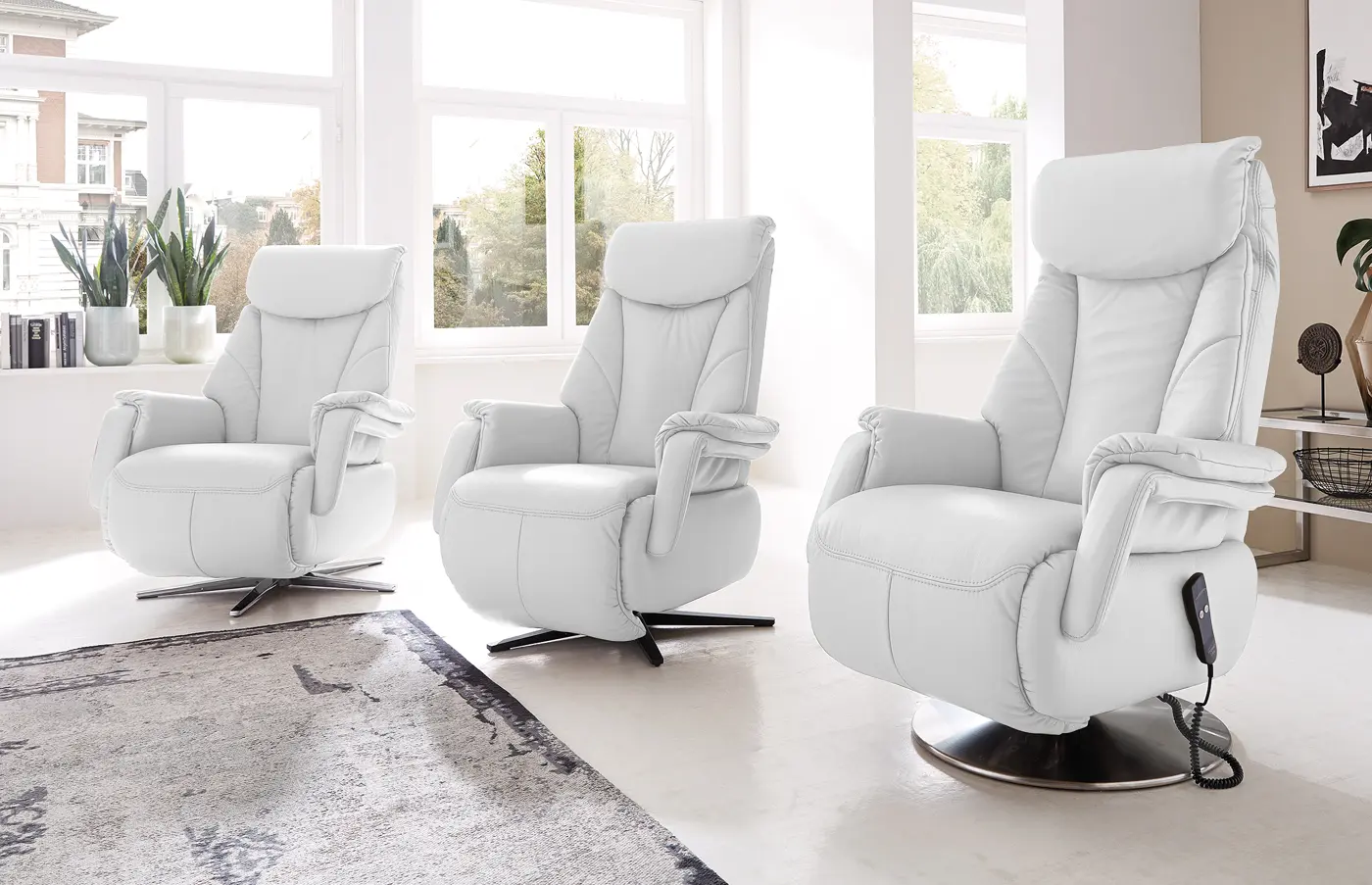 Drei weiße Relaxsessel mit unterschiedlichen Fußgestellen in einem hellen Raum.