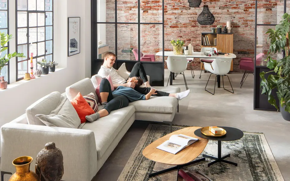 Schön eingerichtetes Wohnzimmer mit Pärchen auf der Couch.