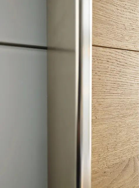 Nahaufnahme von Schrankfront aus Glas und Holz mit Metallprofil