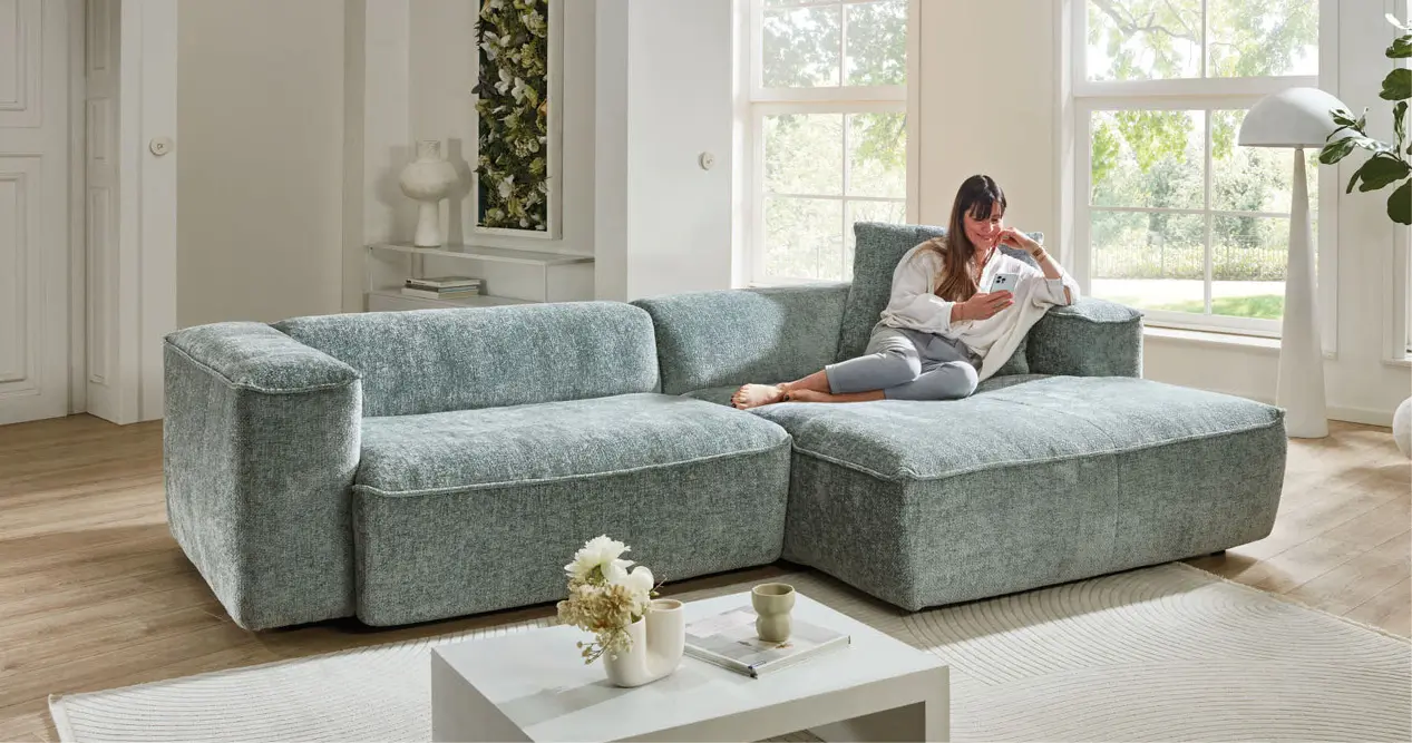 Frau liest auf großer Loungecouch im hellen Wohnzimmer, Couchliebe Lounge.