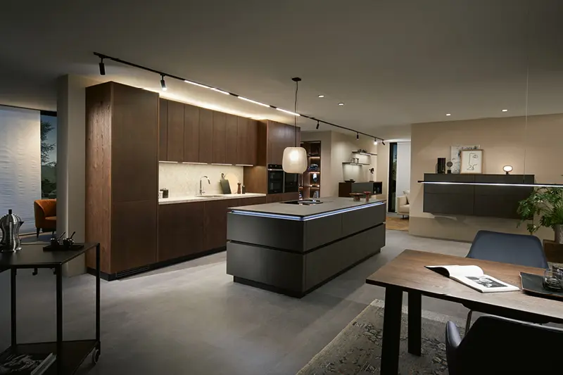 Luxorioese anthrazitfarbene Inselkueche mit Steinarbeitsplatte und Holzfronten in gemuetlichem Wohnbereich.