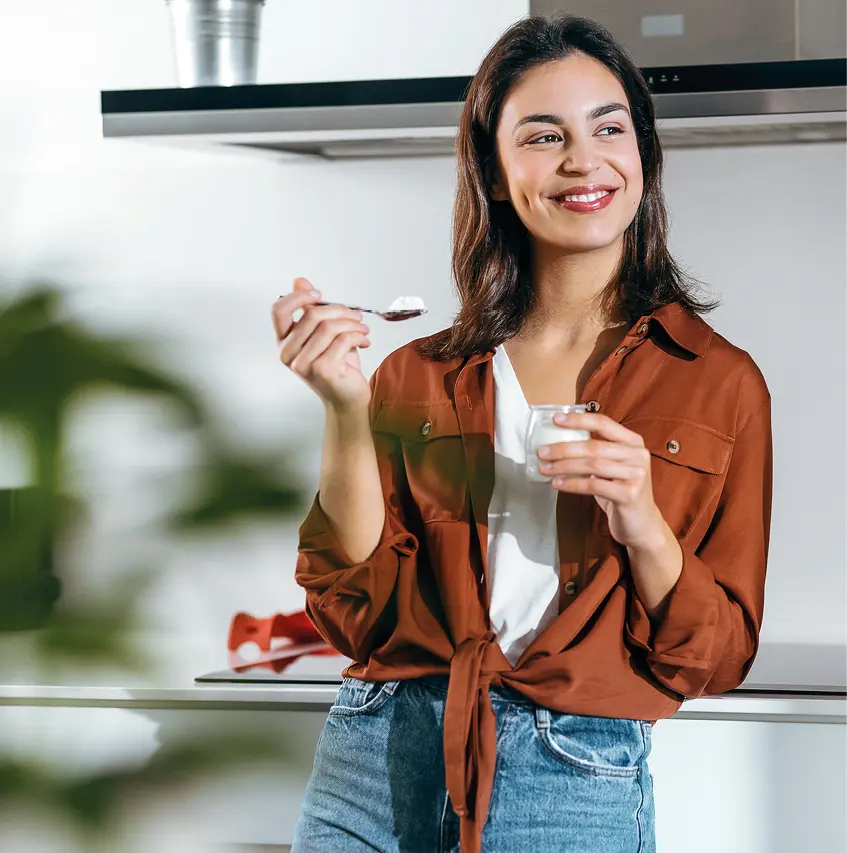Frau probiert Joghurt in moderner Küche, Headerbild kleine Küchen.