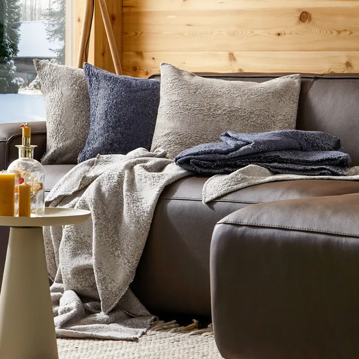 Elegantes Ledersofa von NATURA HOME vor einer Holzwand