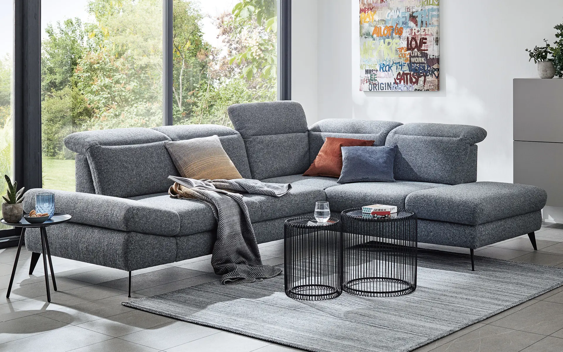Blaugraues Sofa vor Panoramafenster in modernem Wohnzimmer