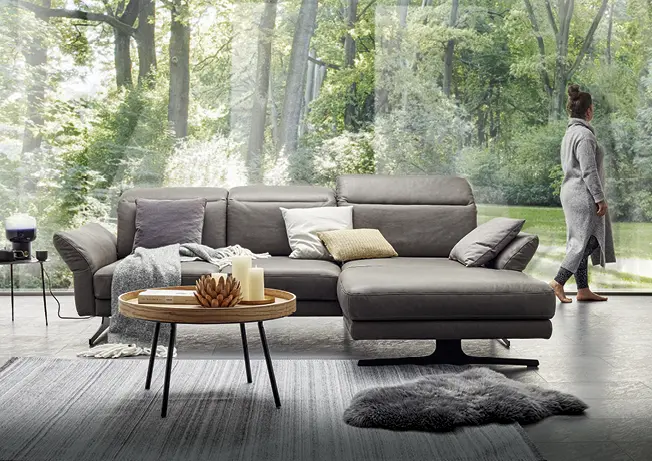 Dunkelgraues Ledersofa vor Panoramafenster mit Couchtisch