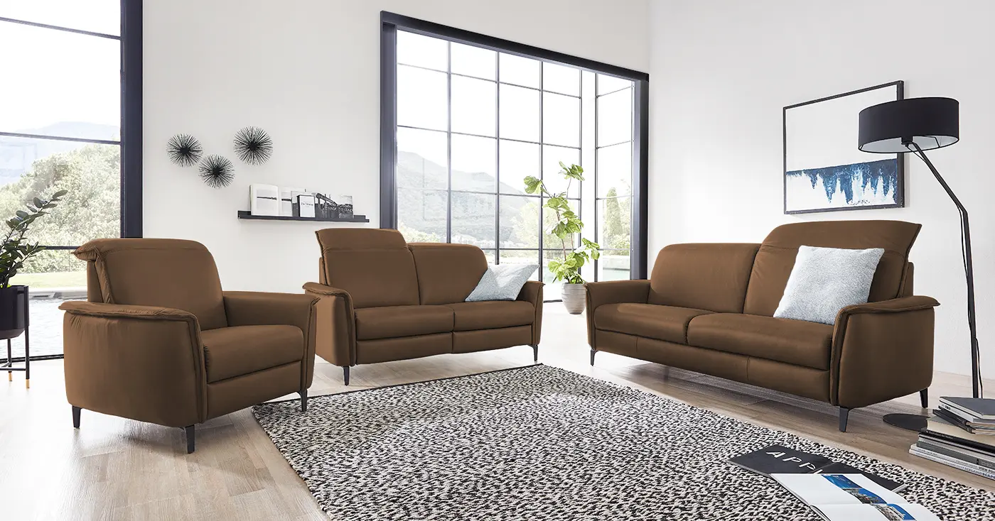 Zwei braune Ledersofa Garnituren mit verstellbarer Kopfstütze und einem dazu passenden Sessel.