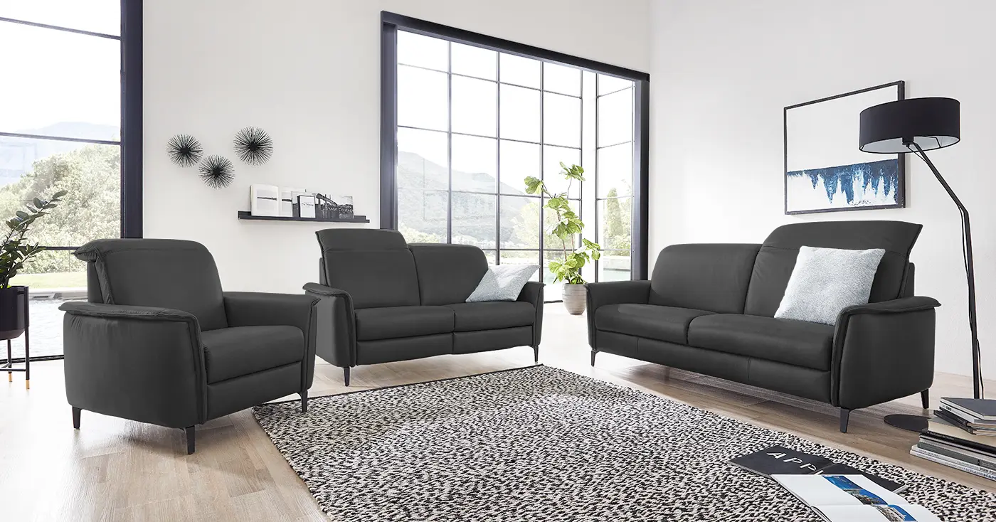 Zwei schwarze Ledersofa Garnituren mit verstellbarer Kopfstütze und einem dazu passenden Sessel.