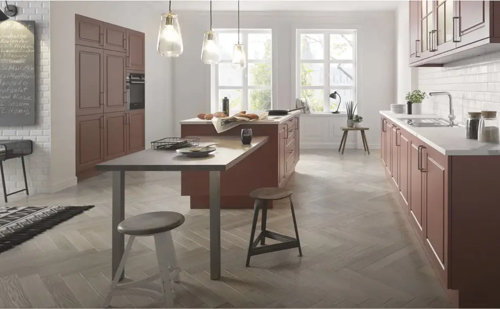 Küche mit roter Front, Kücheninsel mit Arbeitsplatte und zwei Hockern, Pendelleuchten über Insel und Fenster im Hintergrund