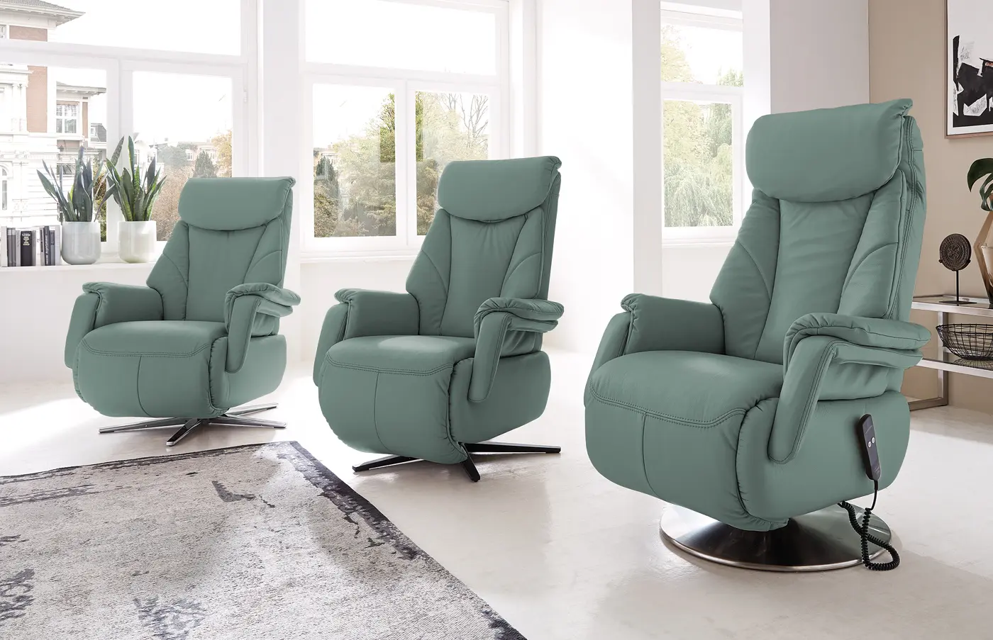 Drei türkise Relaxsessel mit unterschiedlichen Fußgestellen in einem hellen Raum.