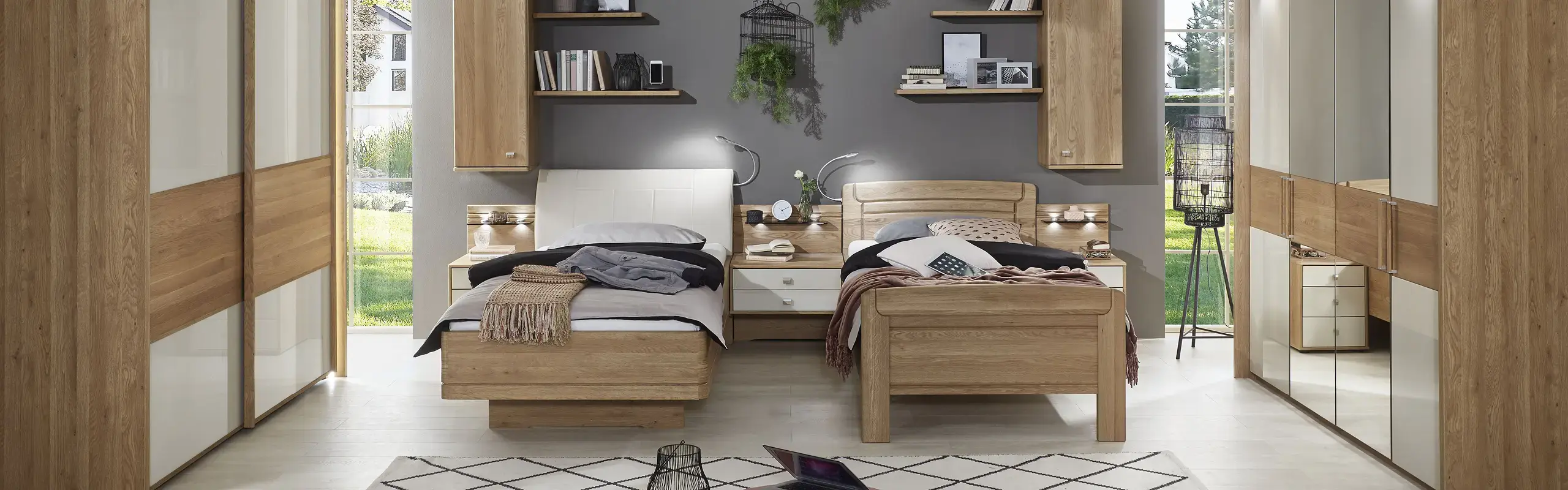Holzbett mit weißer Bettwäsche, großen Kleiderschränken und dunkler Wand