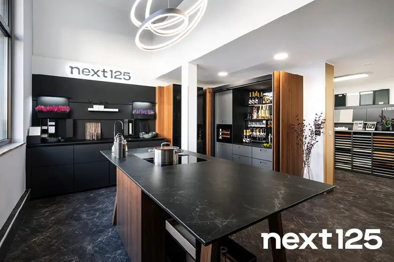 Edle Next125 Kueche mit Next125 Schriftzug und Kuecheninsel aus Holz