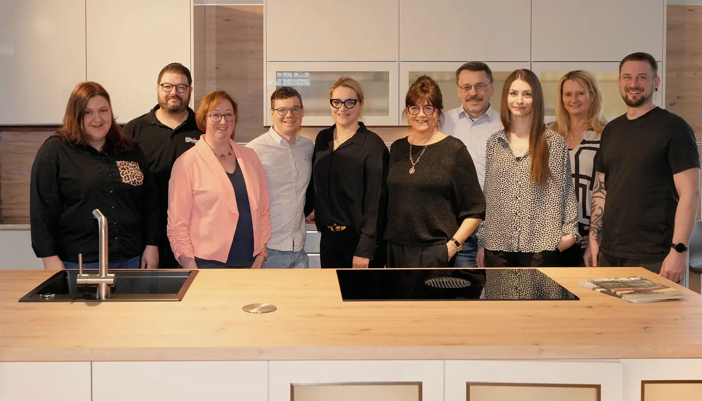 Das Team von Möbel Geigl hinter Kücheninsel im Möbelhaus
